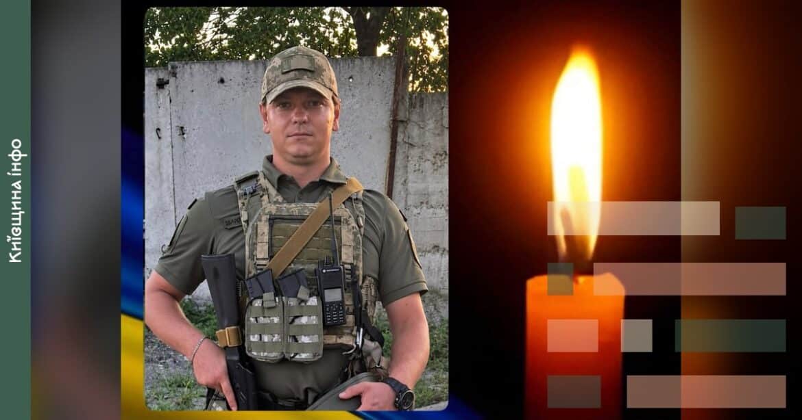 Військовослужбовець у польовій формі та кепці на тлі бетонної стіни, портрет захисника України, та свіча з мерехтливим