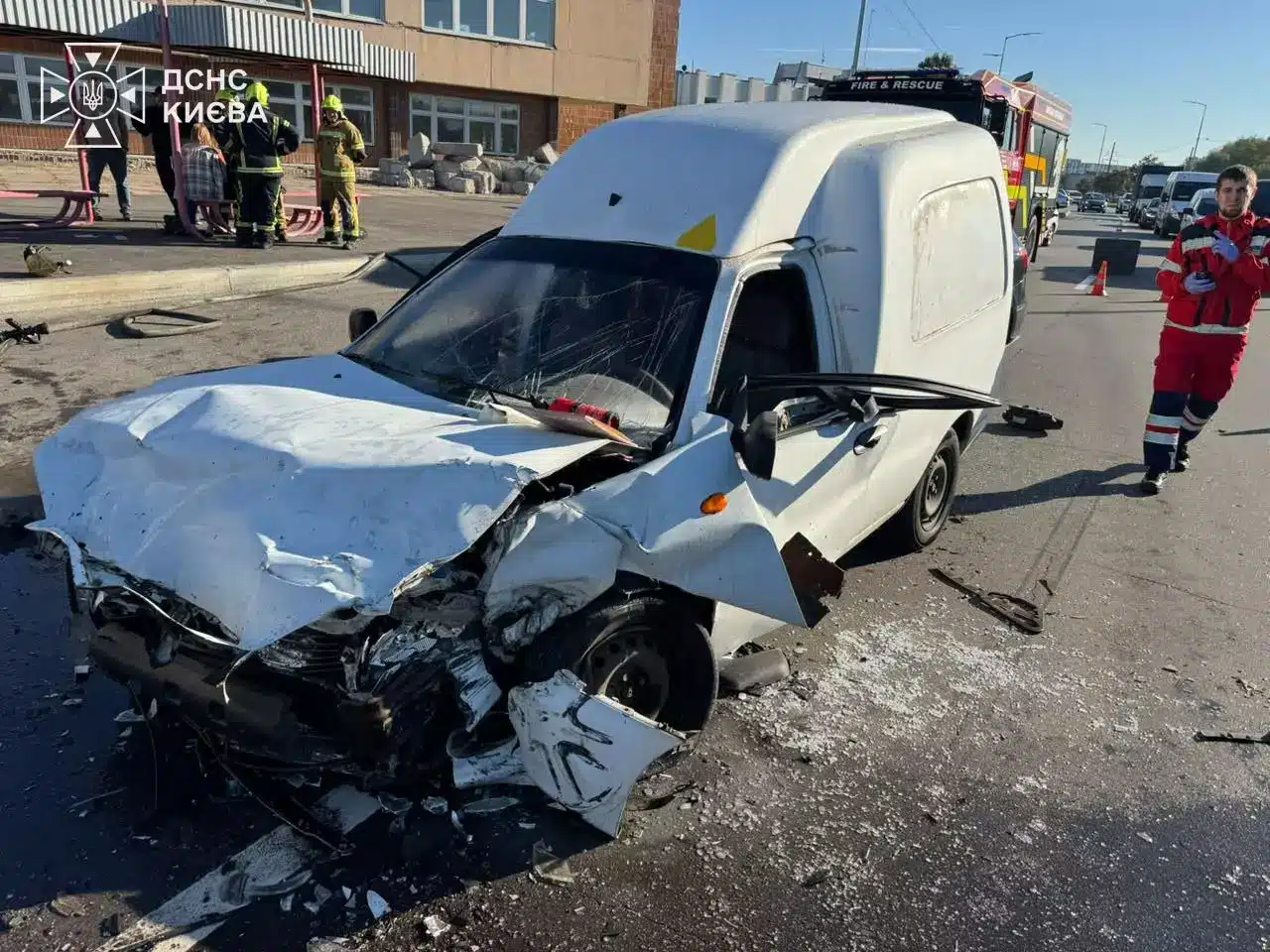 Білий мікроавтобус зі зруйнованою передньою частиною та відкритим капотом, рятувальники та медики біля місця аварії