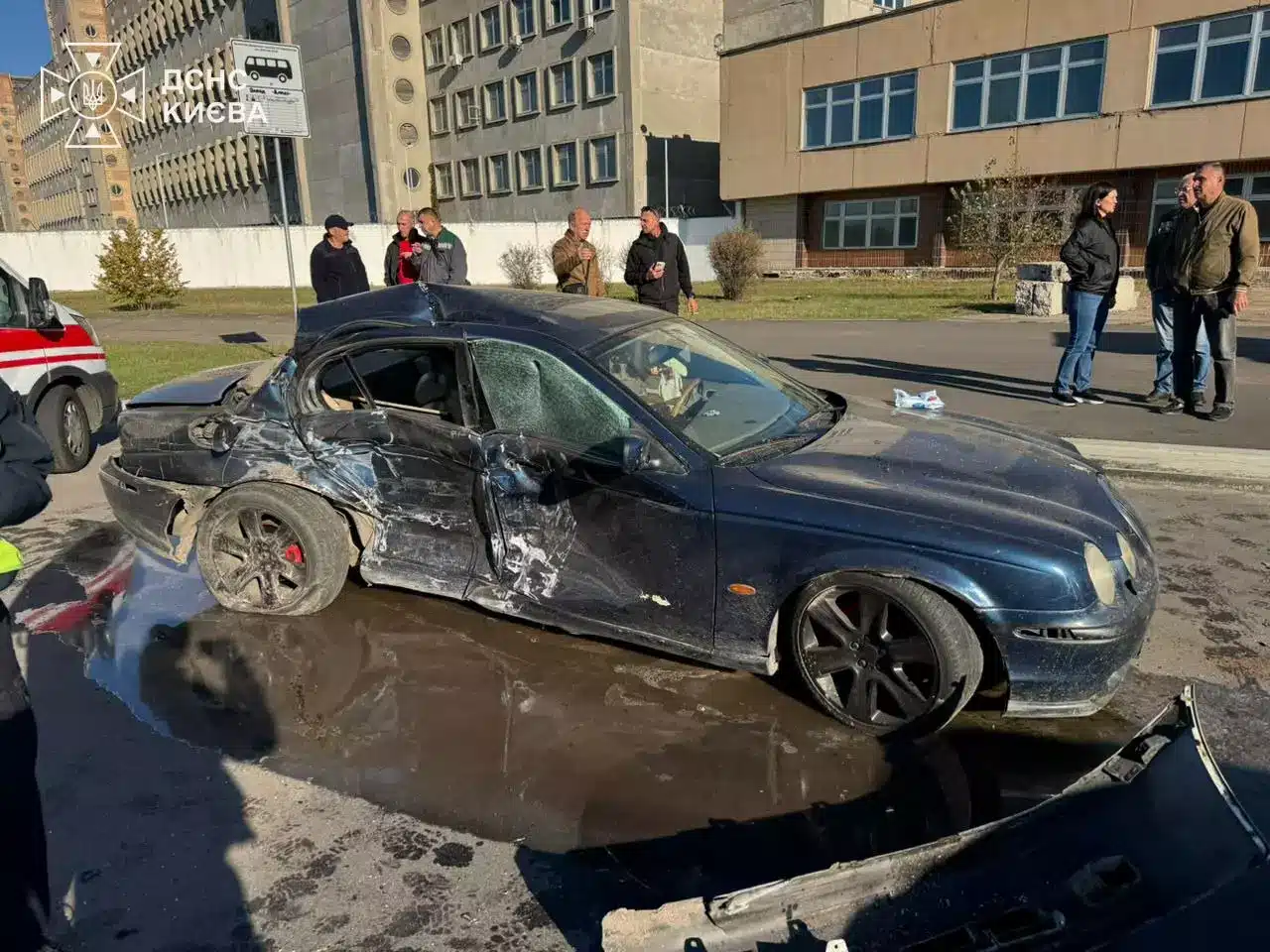 Темно-синій Jaguar зі значною деформацією лівого борту після зіткнення, стоїть у воді на місці ДТП у Києві
