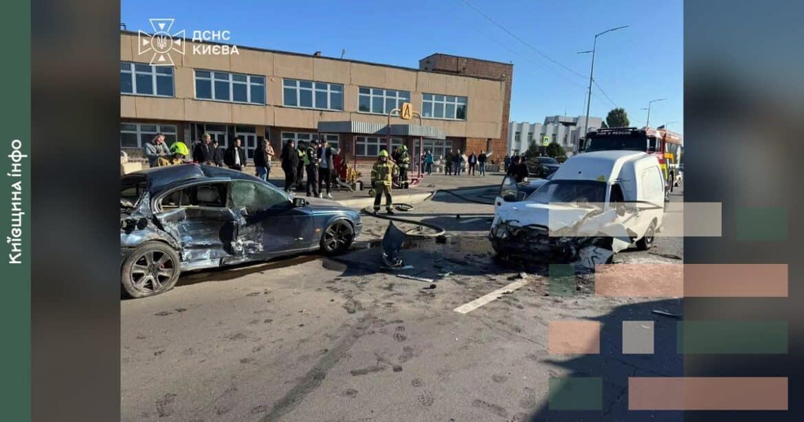 Місце ДТП у Києві з понівеченим чорним автомобілем та білим мікроавтобусом на дорозі біля будинків, рятувальники працюють на
