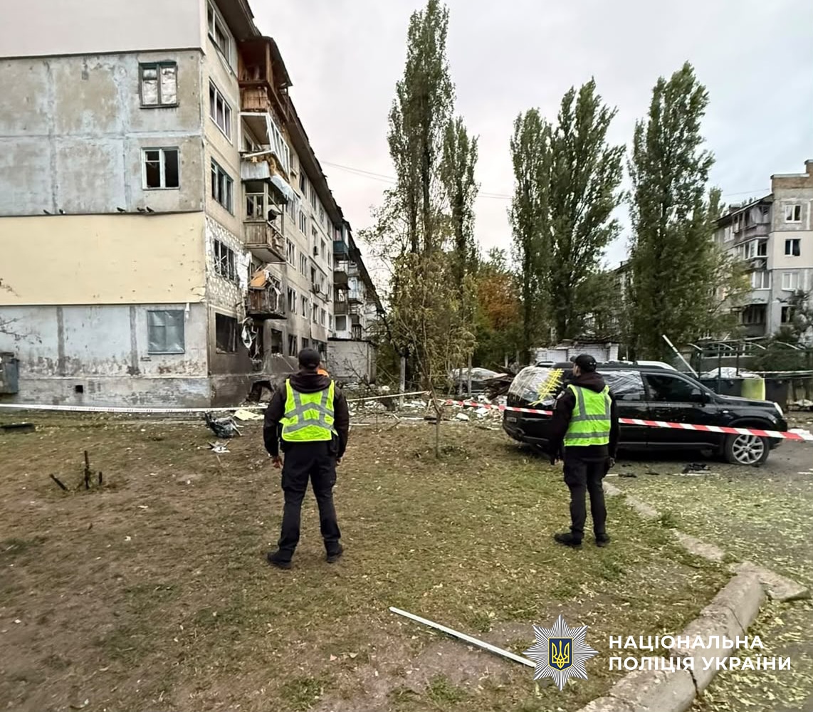 Два поліцейські в жилетах серед завалів на території пошкодженого житлового будинку в Дніпровському районі