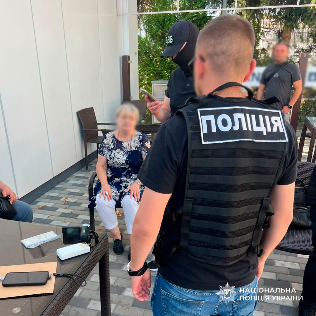 Поліцейський спілкується з жінкою під час затримання на Київщині, біля стола з вилученими речовими доказами
