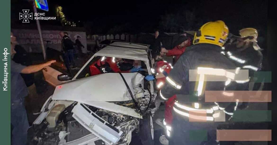 Рятувальники в жовтих касках деблокують постраждалого з понівеченого легкового автомобіля після зіткнення з автобусом у Білій