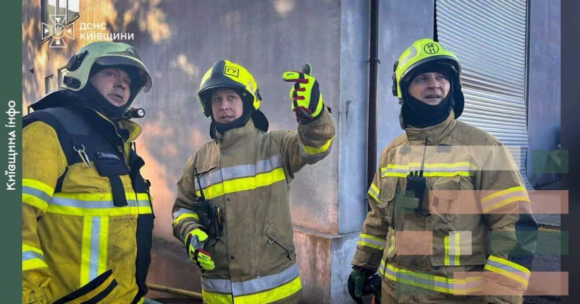 Троє рятувальників у захисному спорядженні з жовтими полосами біля пошкодженої будівлі під час ранкового російського обстрілу