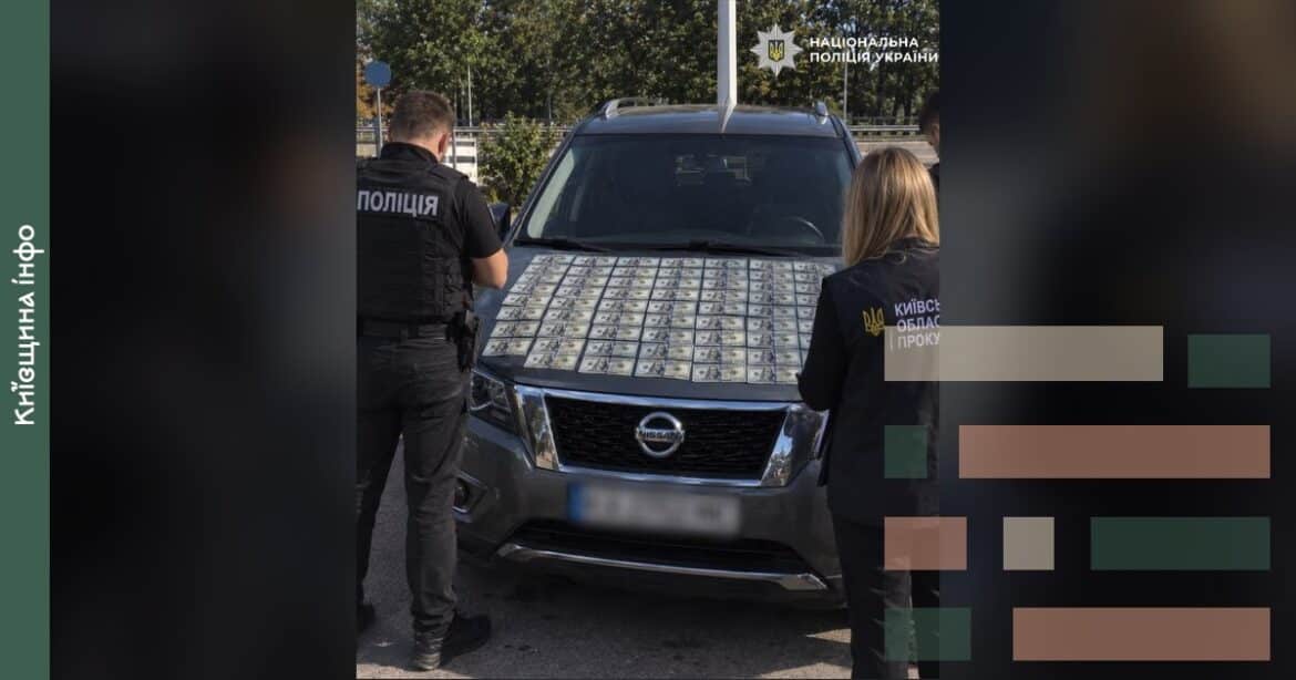 Поліцейські оглядають автомобіль з доларами на капоті під час затримання завідувача кафедри на Київщині