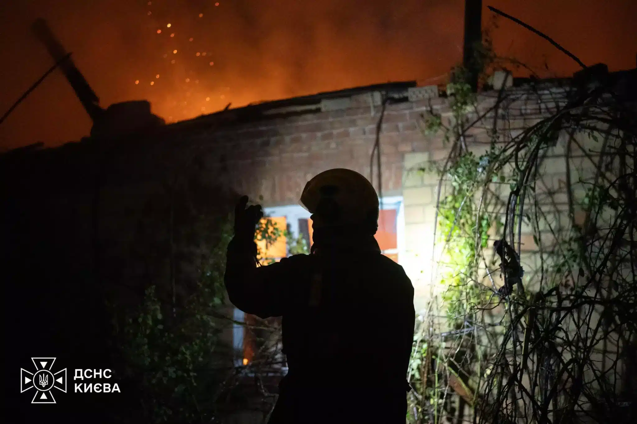 Рятувальник фотографує палаючу будівлю у Святошинському районі під час гасіння пожежі від російського удару