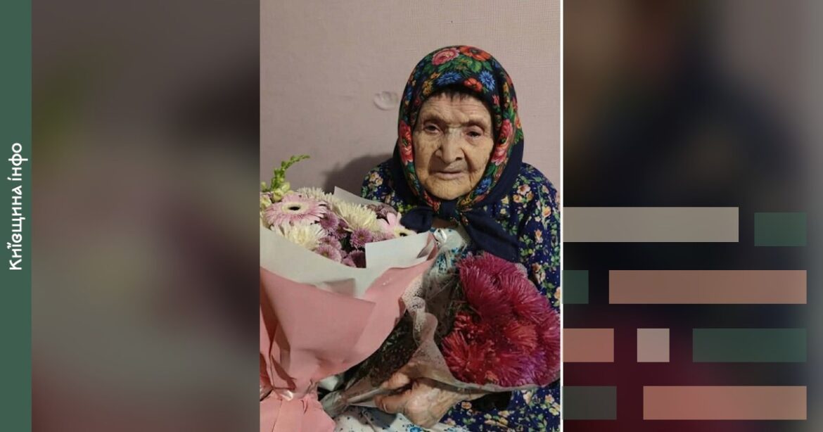 Жінка віком 102 роки в традиційному головному уборі тримає букет квітів на святкуванні дня народження у Харкові