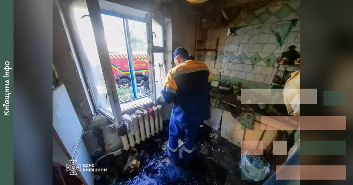 Рятувальники у спеціальному спорядженні евакуюють жінку з палаючої квартири на першому поверсі будинку на вулиці Енергетиків