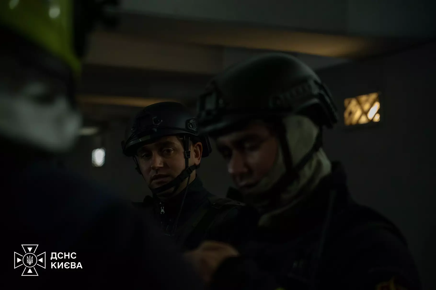 Двоє рятувальників у касках всередині будівлі, освітлюючи приміщення під час пошукових робіт