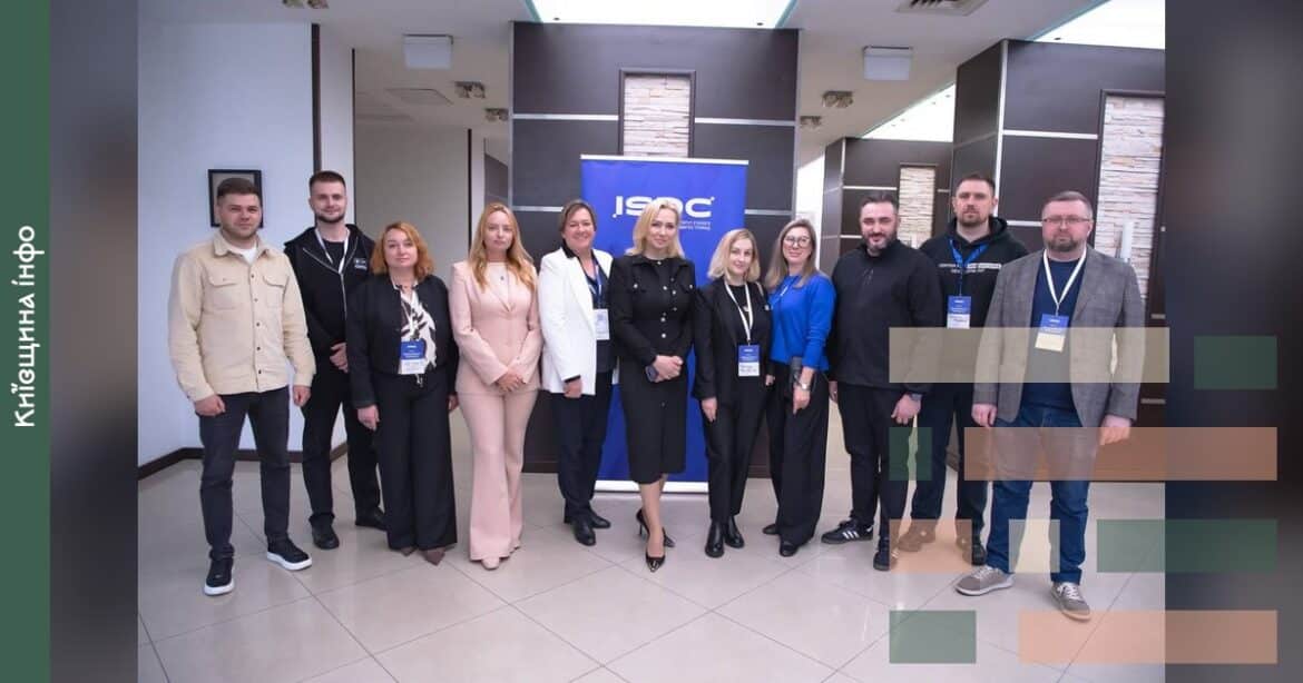Учасники TechnoForum Київщини 2026 в Ірпені позують на фото разом біля логотипу ISAC, представники 12 громад з України