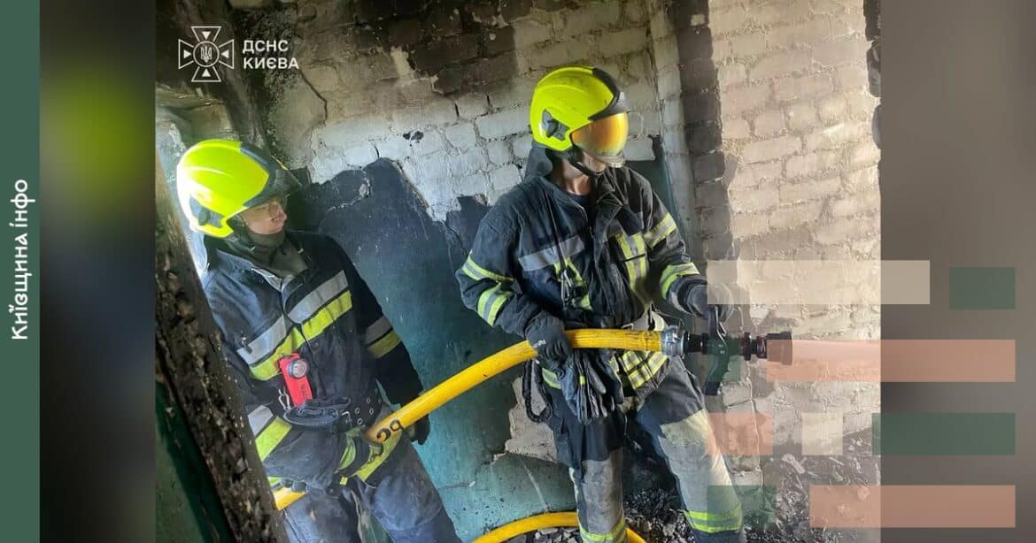 Рятувальники в жовтих касках з пожежним інструментом працюють всередині пошкодженої будівлі після обстрілу Києва