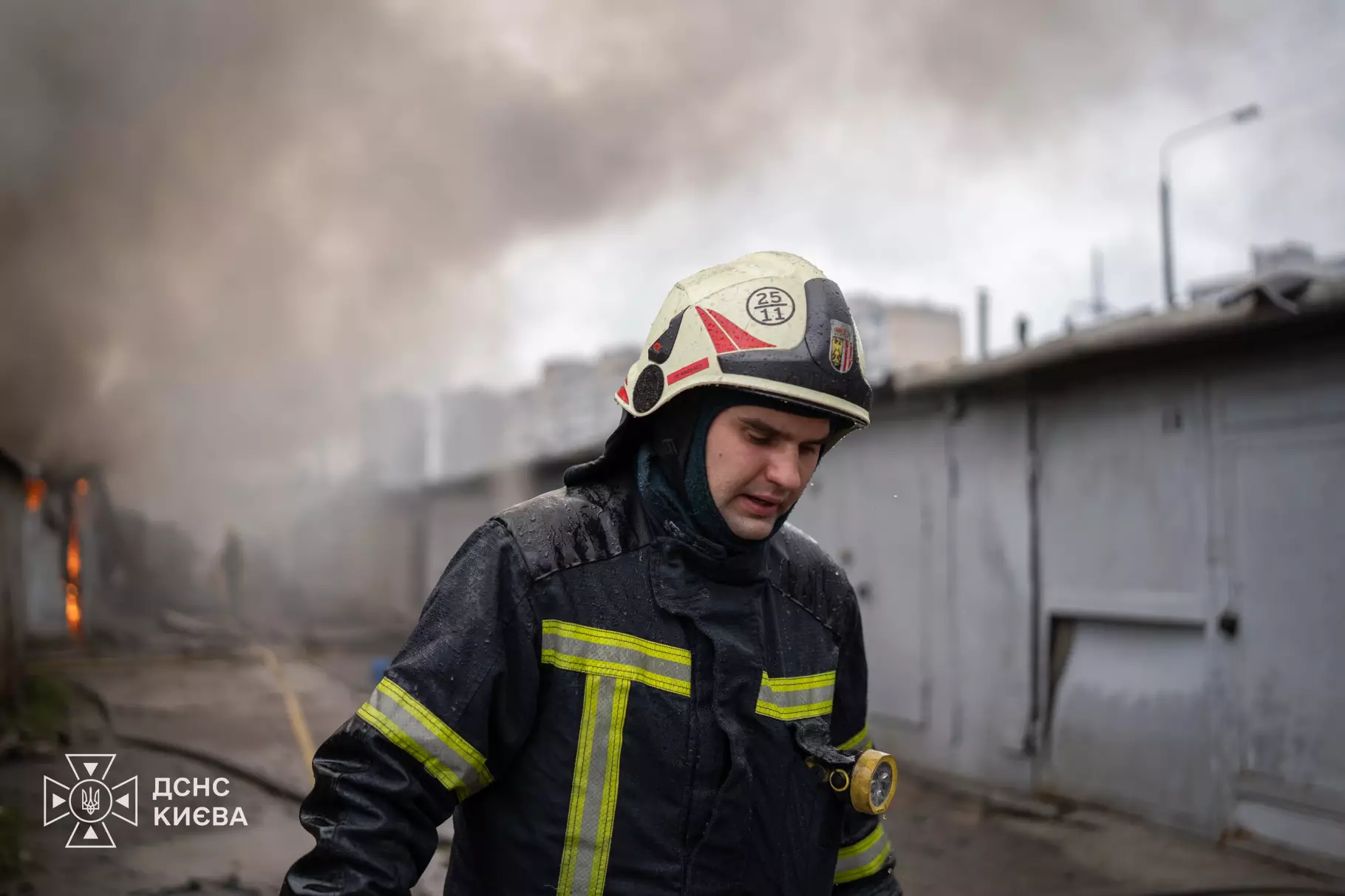 Рятувальник у білому шоломі та темному костюмі на задимленому місці пожежі