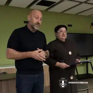 Двоє чоловіків стоять перед аудиторією під час презентації на пам'ятному заході