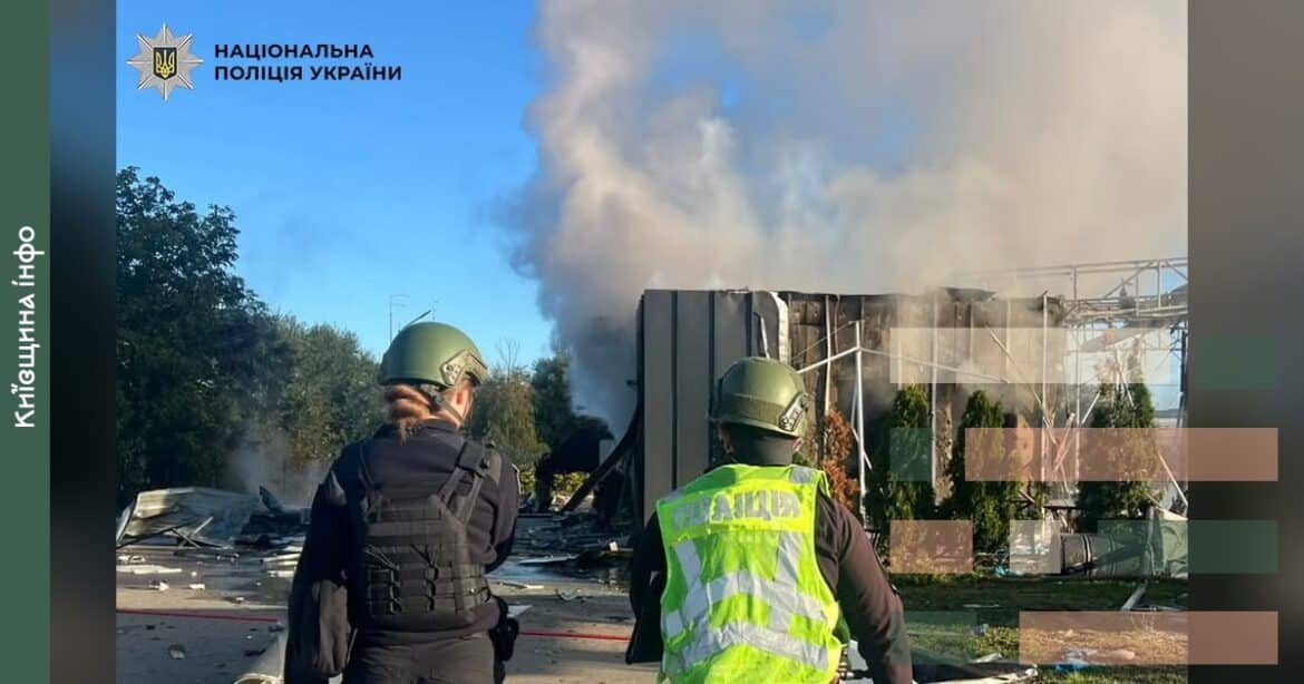Поліцейські в касках та захисному спорядженні біля палаючої будівлі АЗС з димом і вогнем після ракетної атаки у Києві