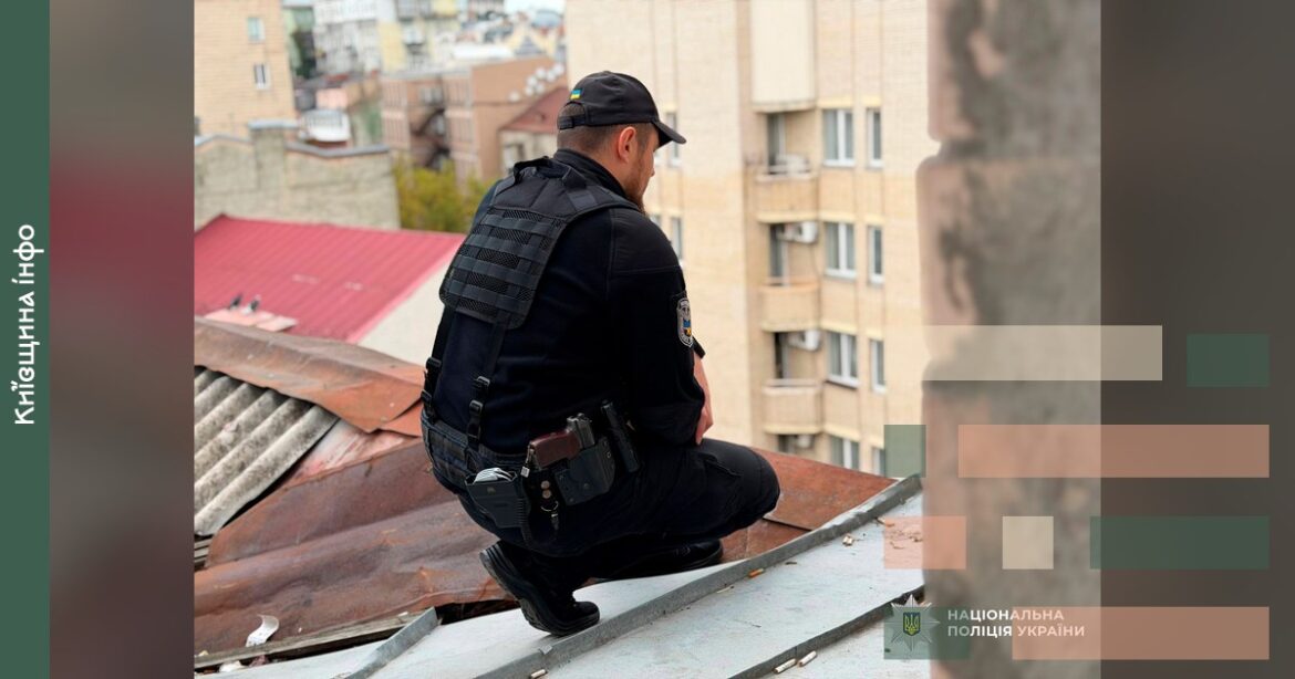 Поліцейський у чорній формі сидить на даху п'ятиповерхового будинку під час операції порятунку