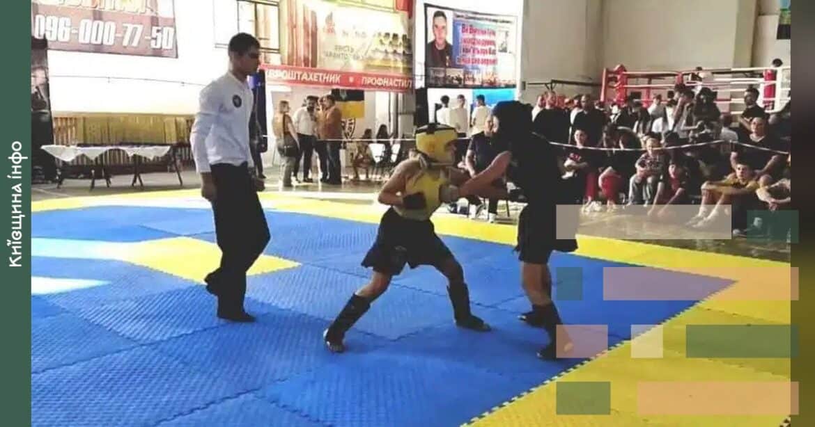 Молода спортсменка в чорному кімоно виконує прийом під час поєдинку з хортингу на сцені з сіжою на матах перед глядачами