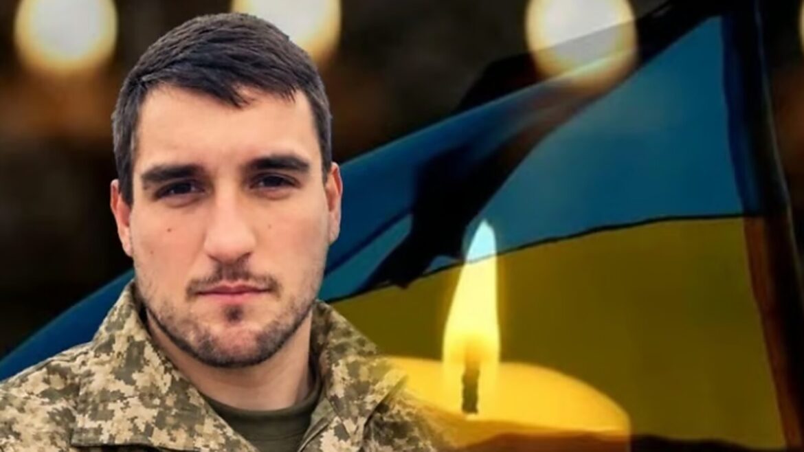 Військовий у камуфльованій формі біля українського прапора під час траурної церемонії