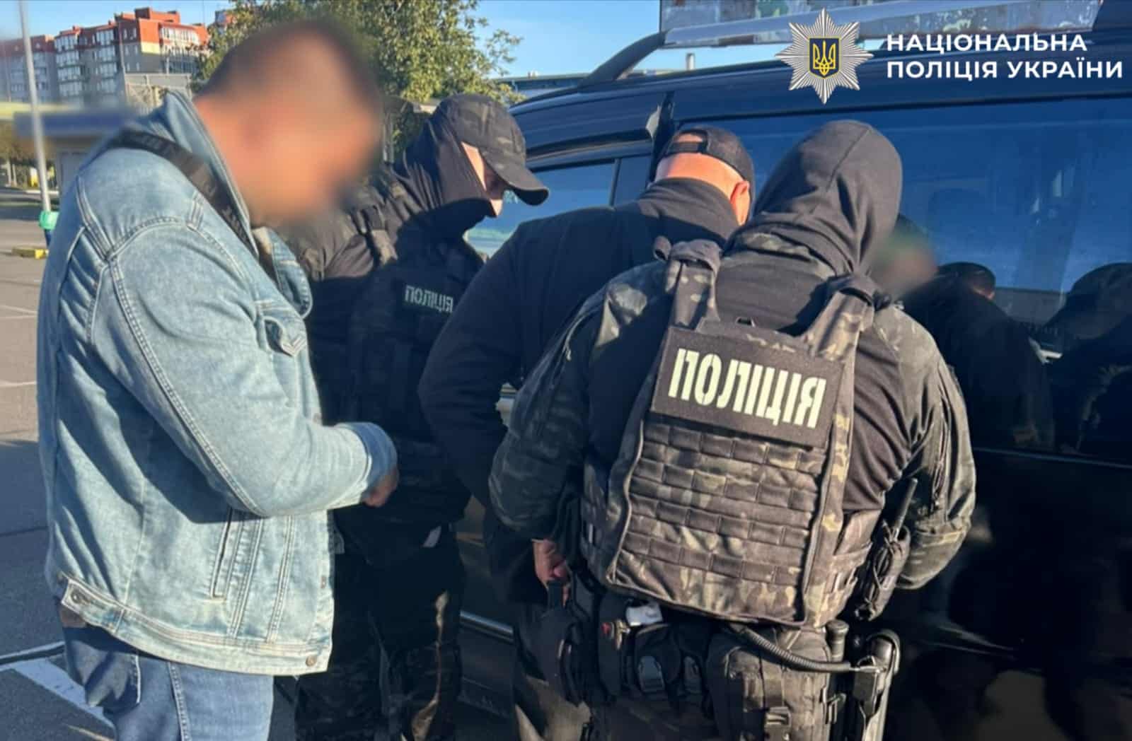 Затриманий чоловік у супроводі поліцейських біля служебного автобуса