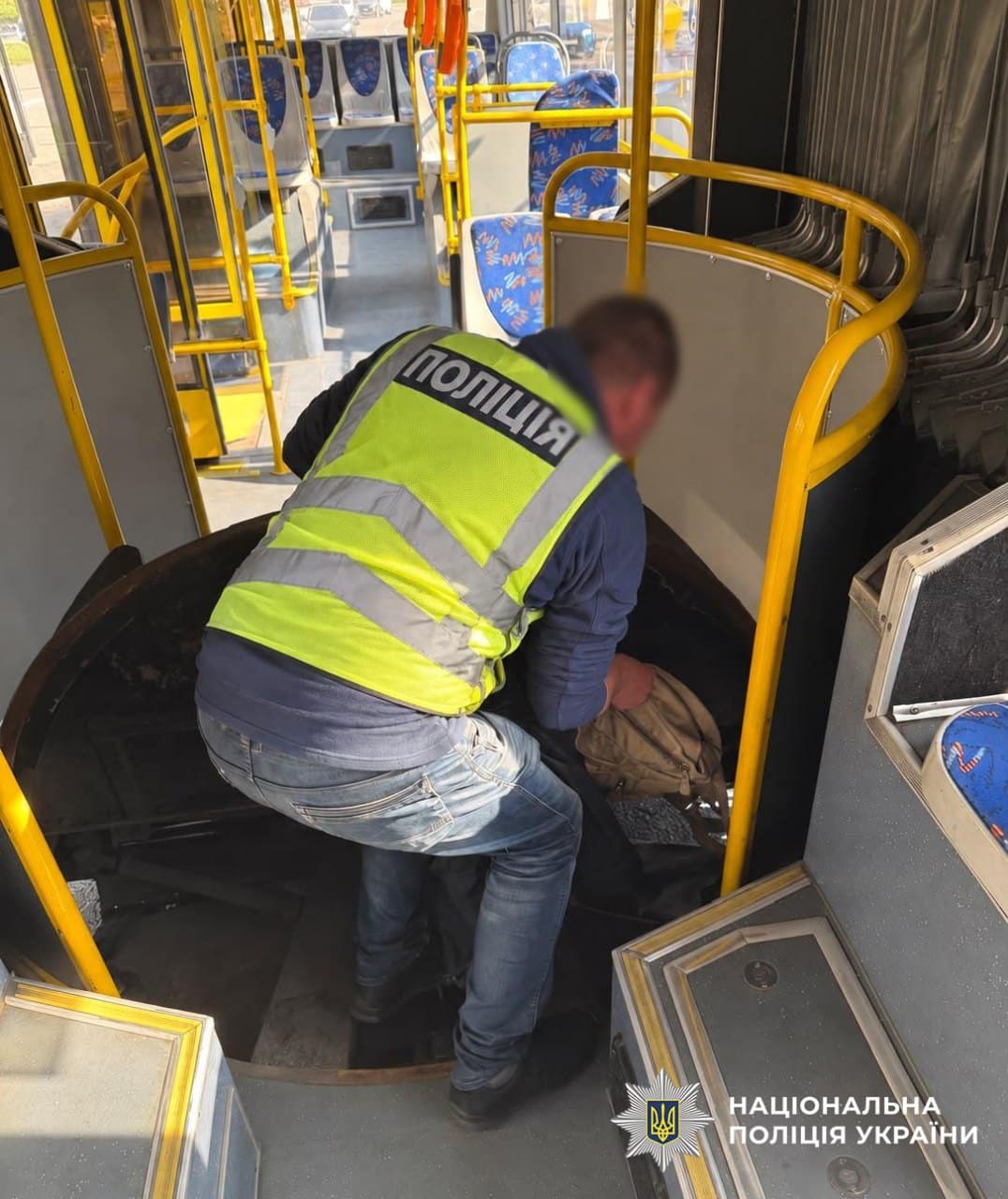 Поліцейський розбирає механізм гофрованого чохла під сидінням автобуса для витягування втрачених речей