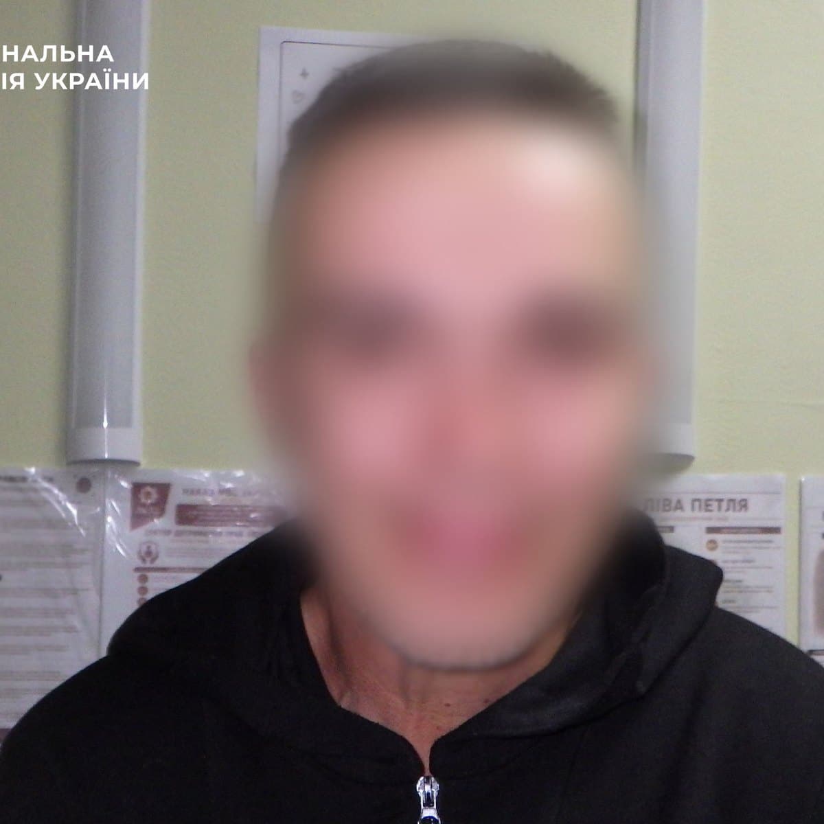 Затриманий чоловік на фоні поліцейського відділення Національної поліції України