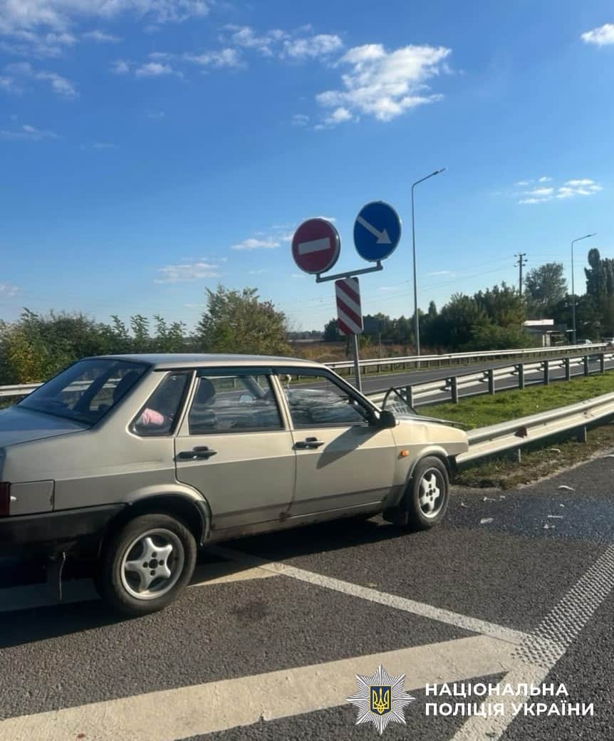 Легковик ВАЗ з пошкодженнями біля дорожного знака на автотрасі