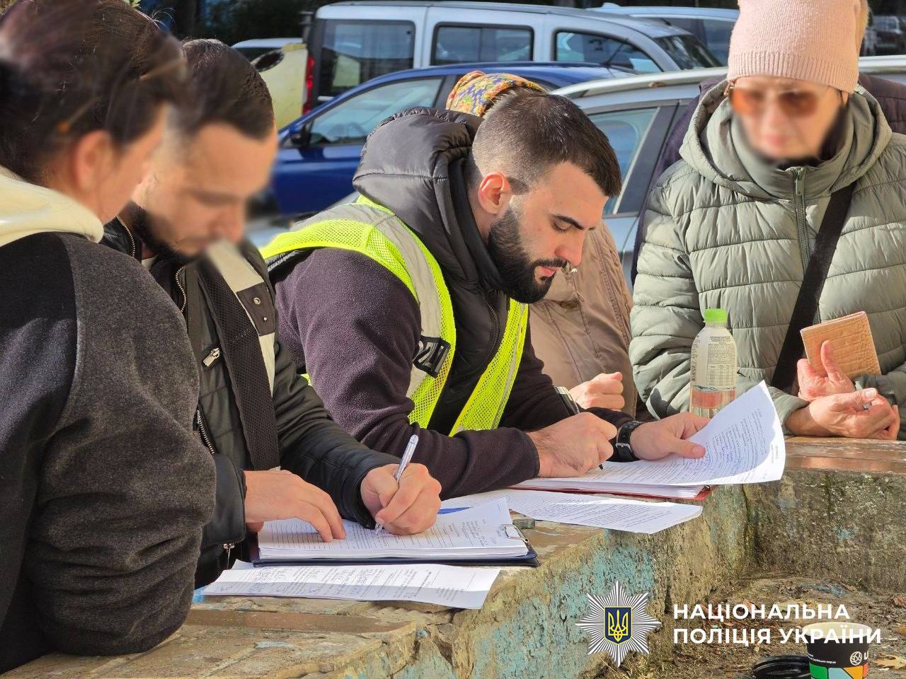 Поліцейський у жилеті заповнює документи під час прийому заяв від постраждалих мешканців
