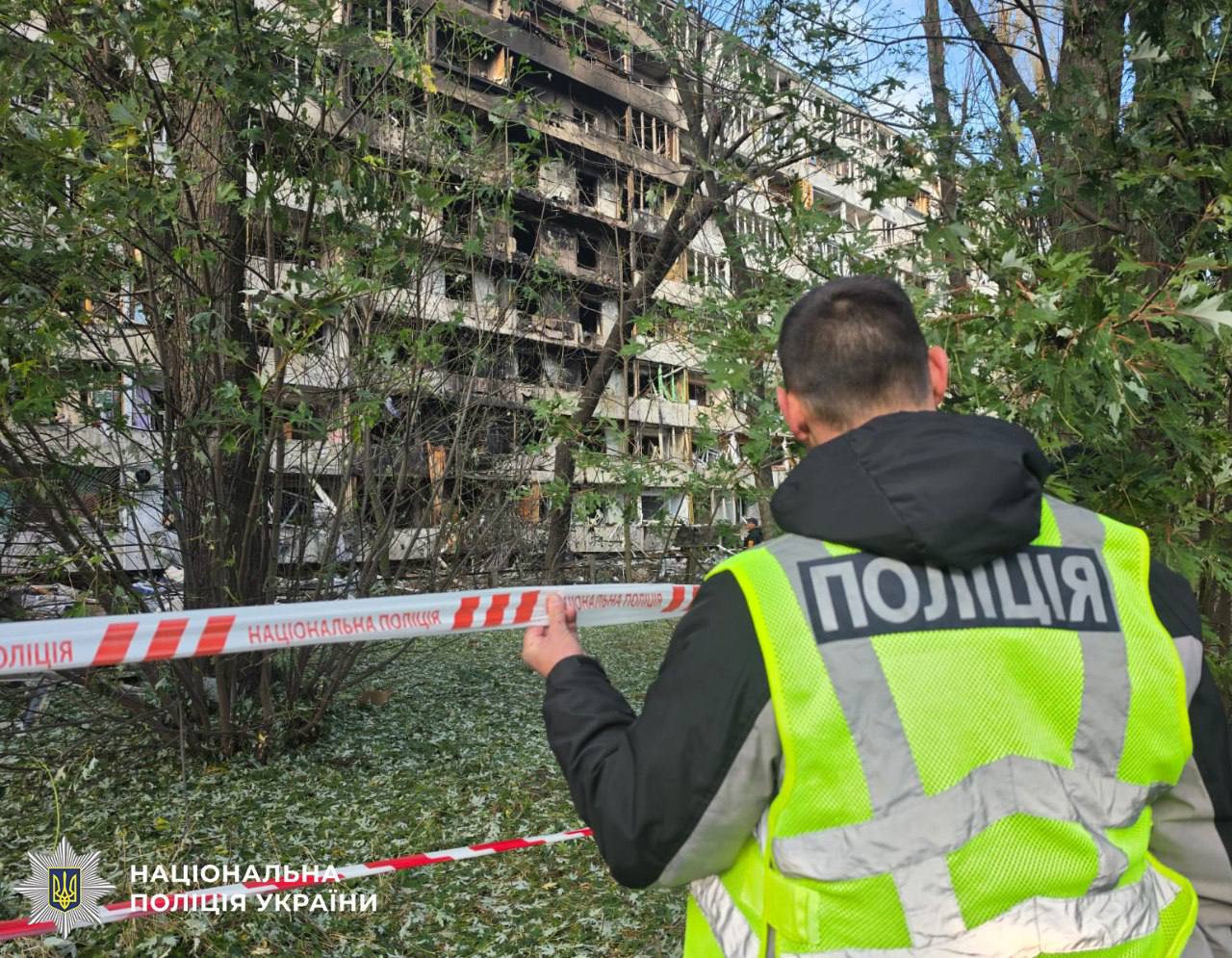 Поліцейський перекриває оградою пошкоджений багатоквартирний житловий будинок у Деснянському районі