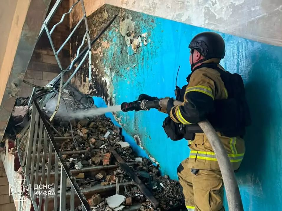 Рятувальник у захисному костюмі подає воду з гідранта на зруйновану частину будівлі під час гасіння пожежі