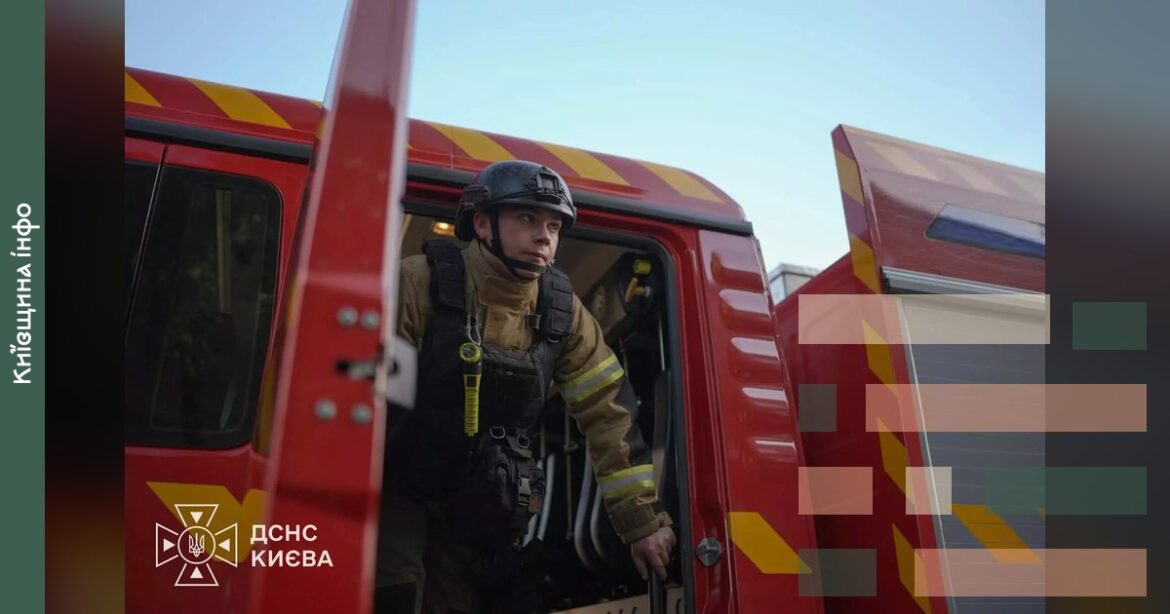 Рятувальник у жовто-чорному костюмі та касці сидить у кабіні червоного пожежного автомобіля ДСНС Києва