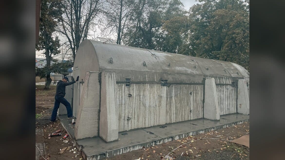 Модульне укриття для пасажирів на залізничній станції у Глевасі, чоловік оглядає конструкцію зі сірих панелей