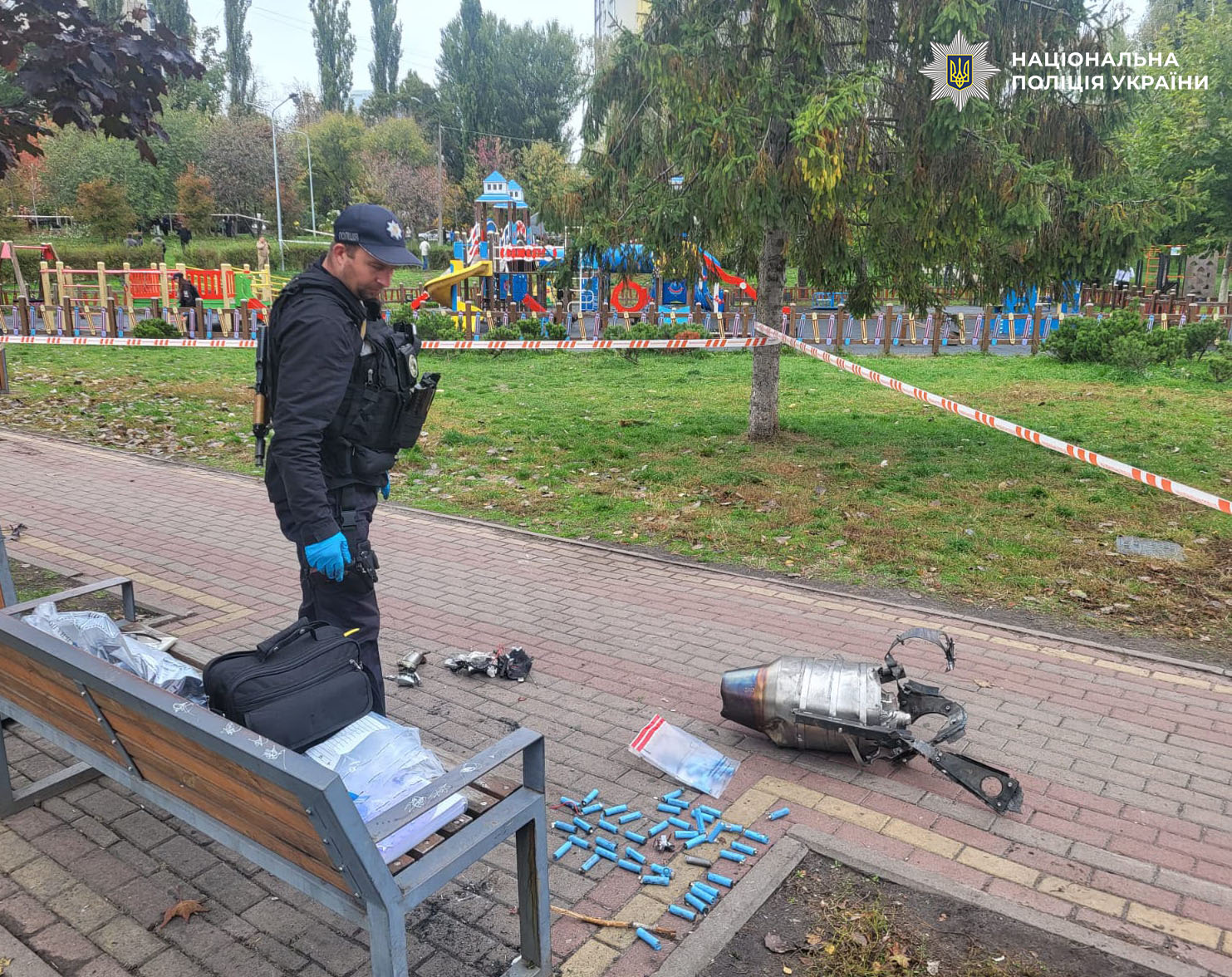 Поліцейський документує деталі дрона та його компоненти на набережній біля дитячого майданчика