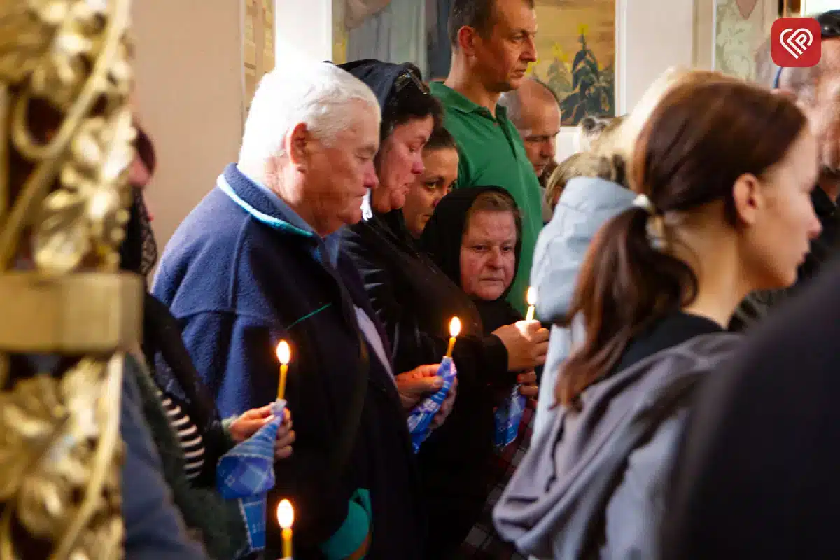Люди зі свічками молять в храмі під час богослужіння за упокій душі загибло воїна