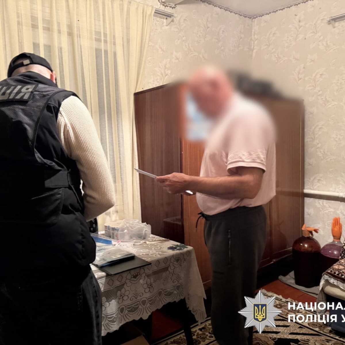 Поліцейський беседує з чоловіком під час проведення слідчих дій у кімнаті
