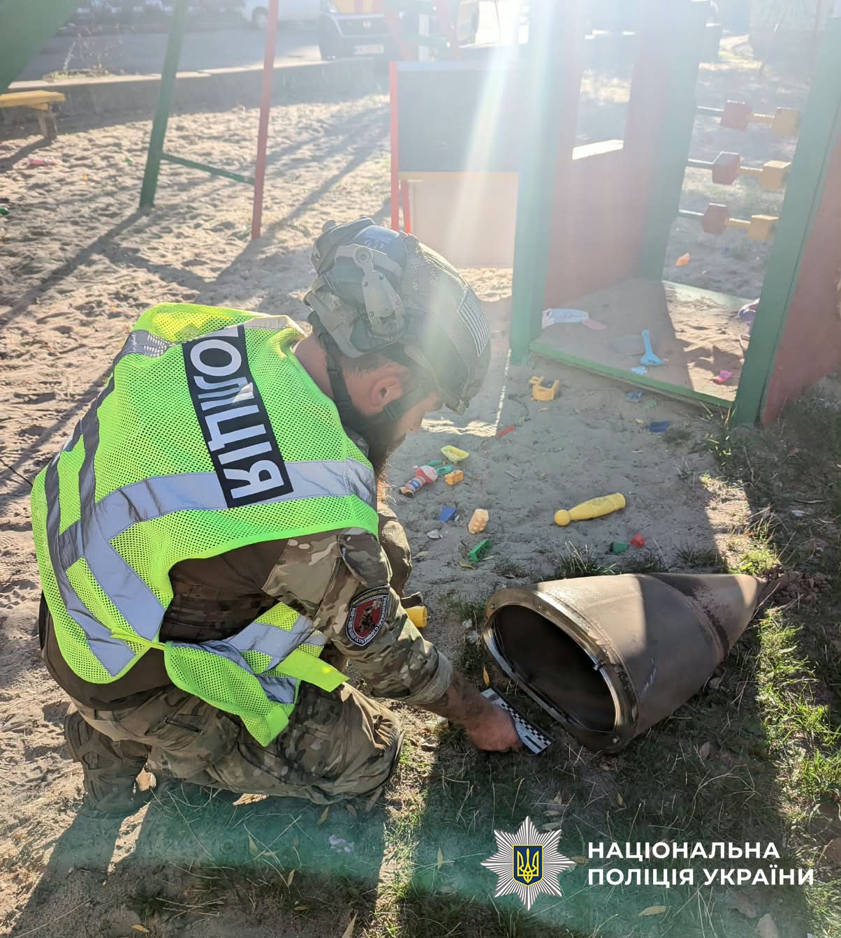 Рятувальник розглядає осколок з позначеннями на місці удару в Киї