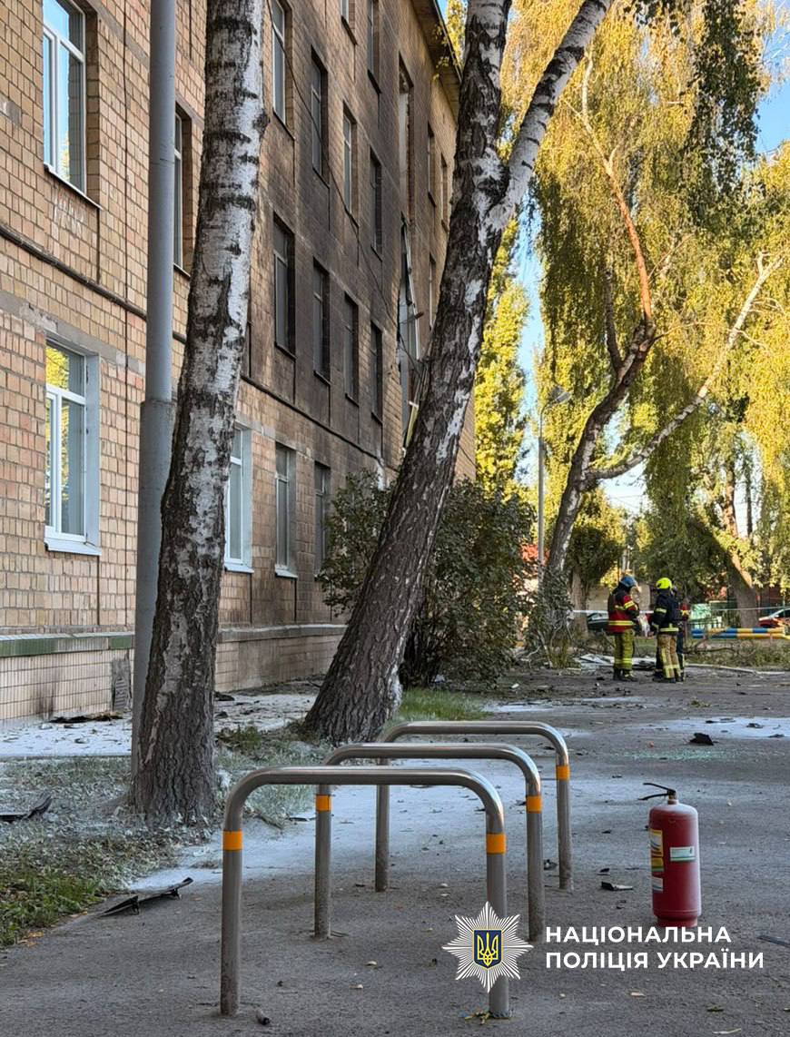 Двір школи з пошкодженою берізою та слідами атаки, де працюють рятувальники