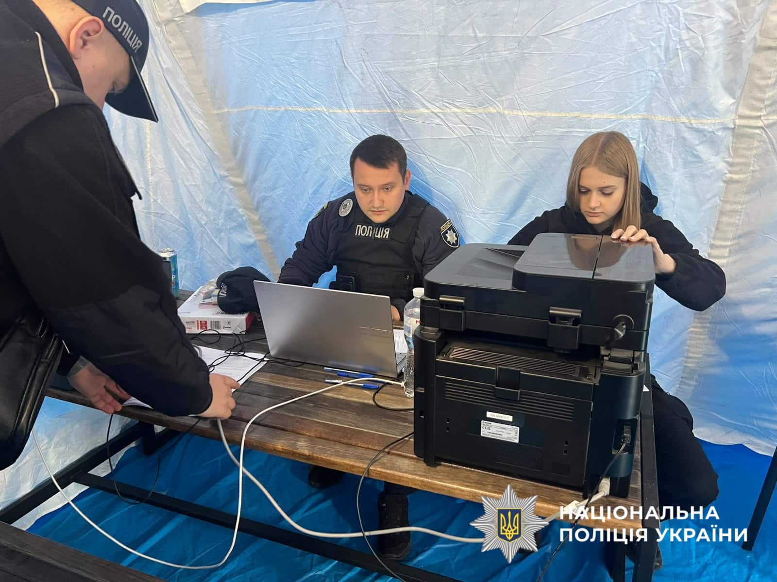 Поліцейські документують наслідки атаки, працюючи з ноутбуком і принтером у польовій намет