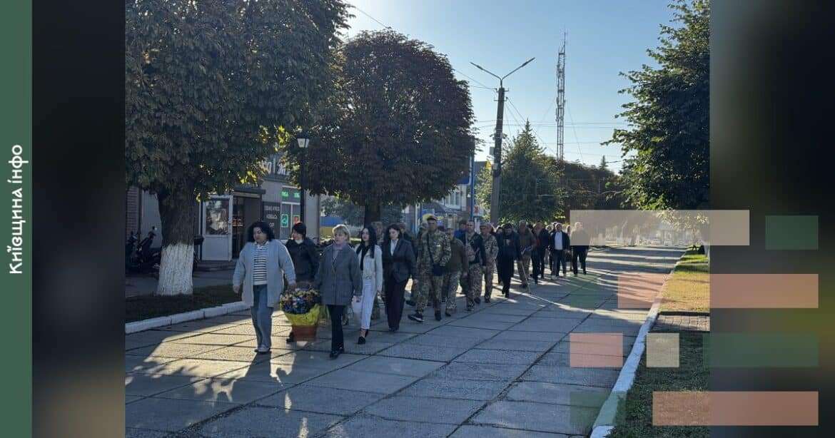 Люди йдуть по центральній алеї селища під час урочистого заходу