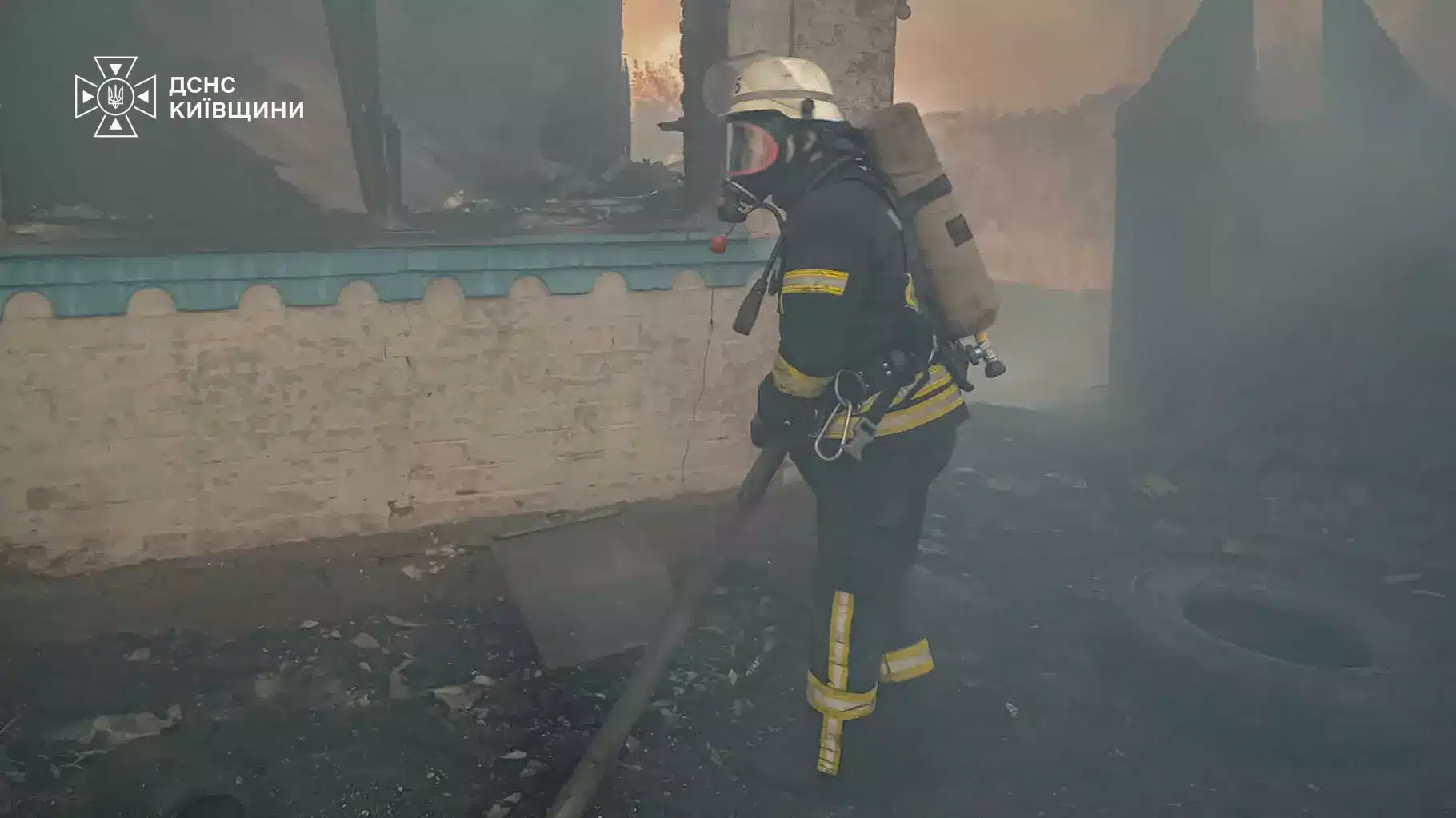 Рятувальник у касці та захисному одязі видно крізь дим під час гасіння пожежі в селі Тайниця