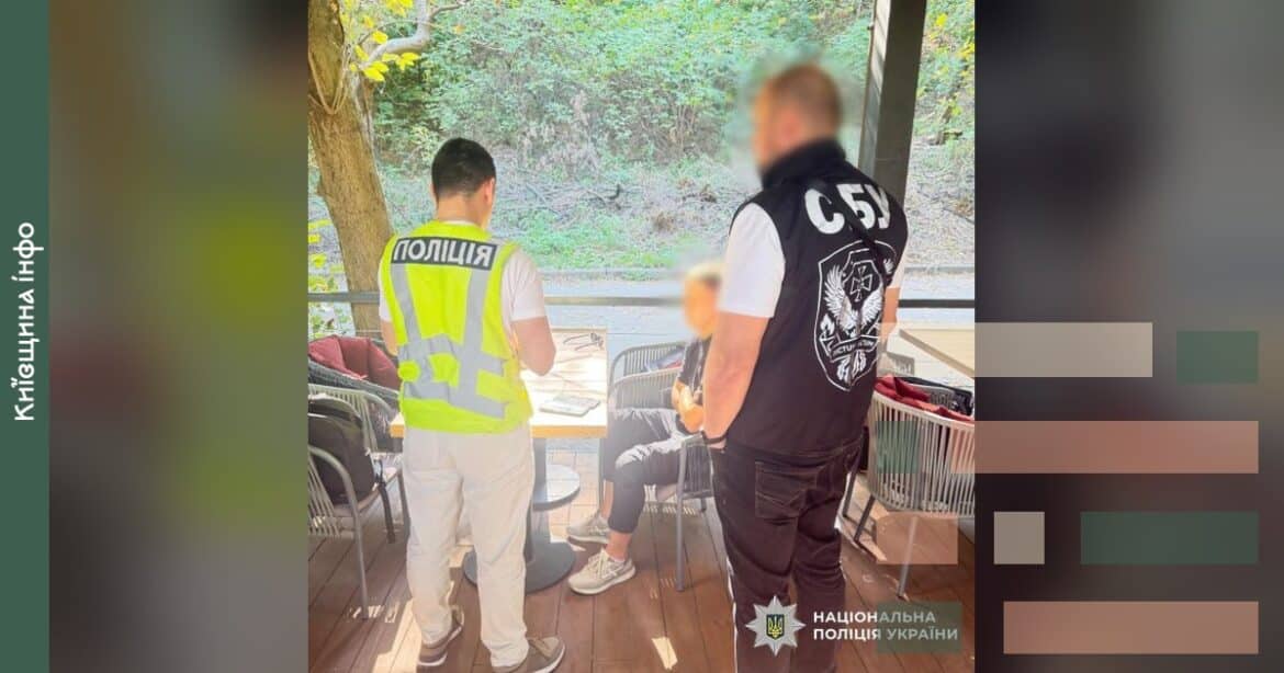 Поліцейський у жилеті затримує чоловіка в кафе під час операції з затримання адвоката, який пропонував схеми уникнення