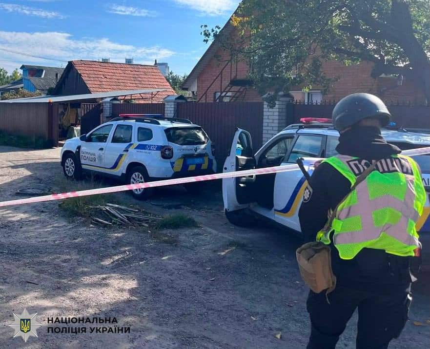 Поліцейські автомобілі з червоно-білою стрічкою огородження біля житлового будинку у Солом'янському районі