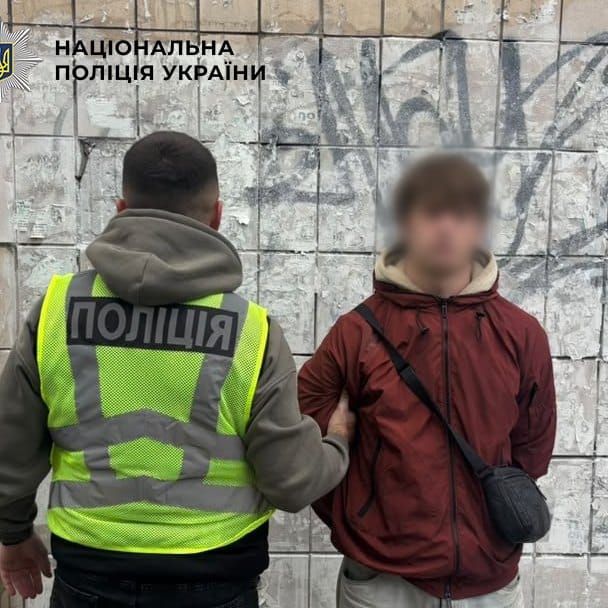 Поліцейський супроводжує затриманого молодика під час проведення операції на Святошинщині