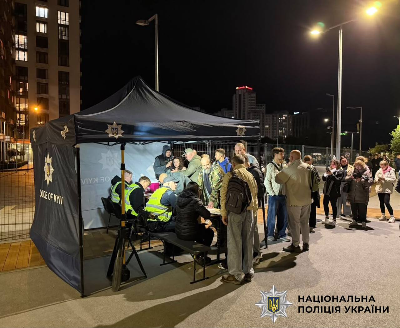 Поліцейські беруть показання від потерпілих під палаткою на місці атаки безпілотника на житлову будівлю