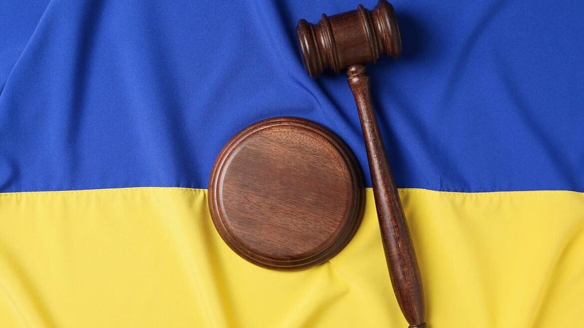 Судовий молоток на дереві на фоні українського прапора, символізуючи судове рішення щодо повернення землі громаді